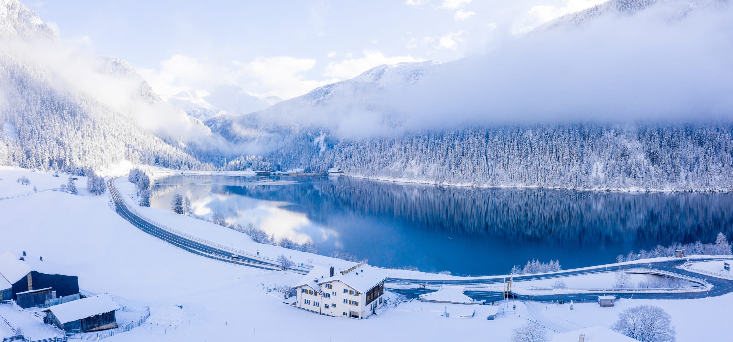 A frozen alpine lake ringed by snow-covered trees in the mountains above Davos