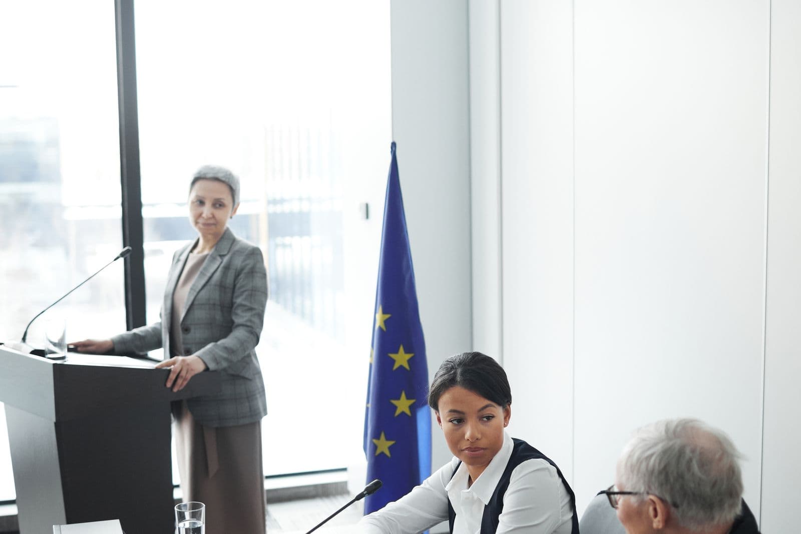 A delegate speaking from a podium as others look on at a conference table