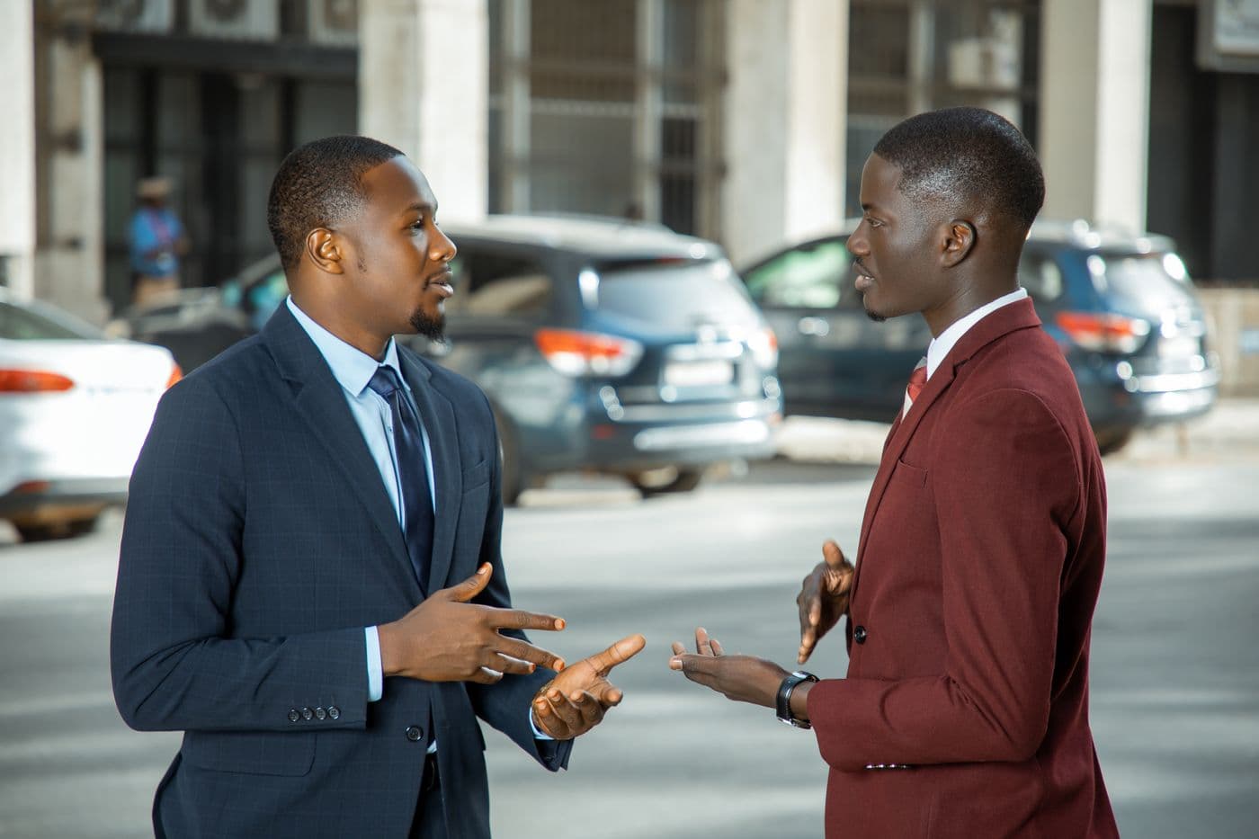 Two people in tailored suits in conversation outside an office building