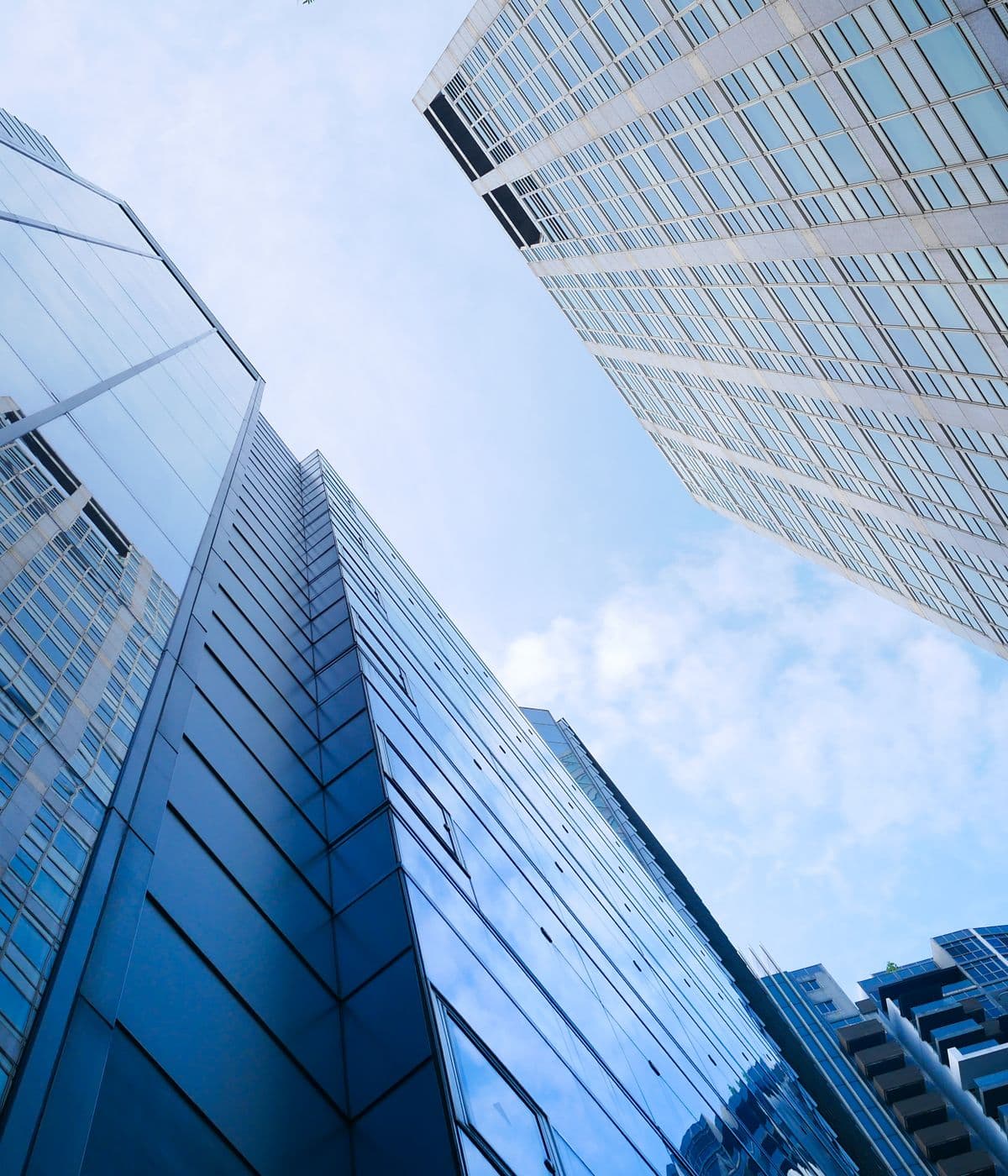 Glass corporate towers photographed looking upwards against an open sky