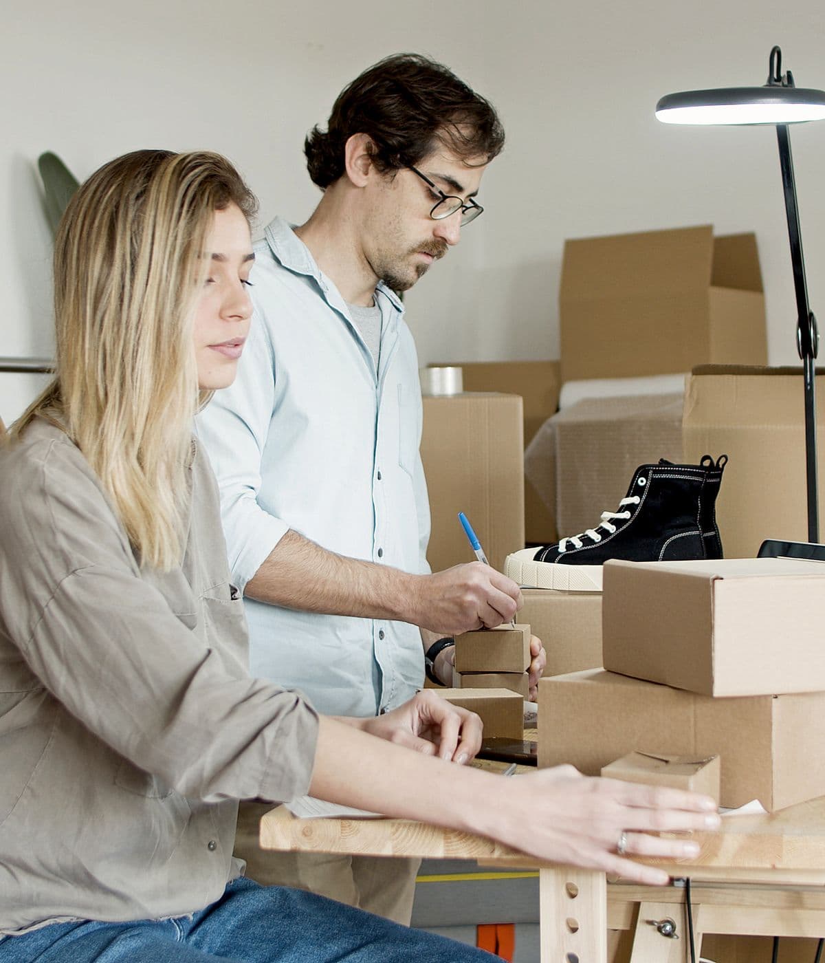 Two small business owners packing orders into boxes in their workshop