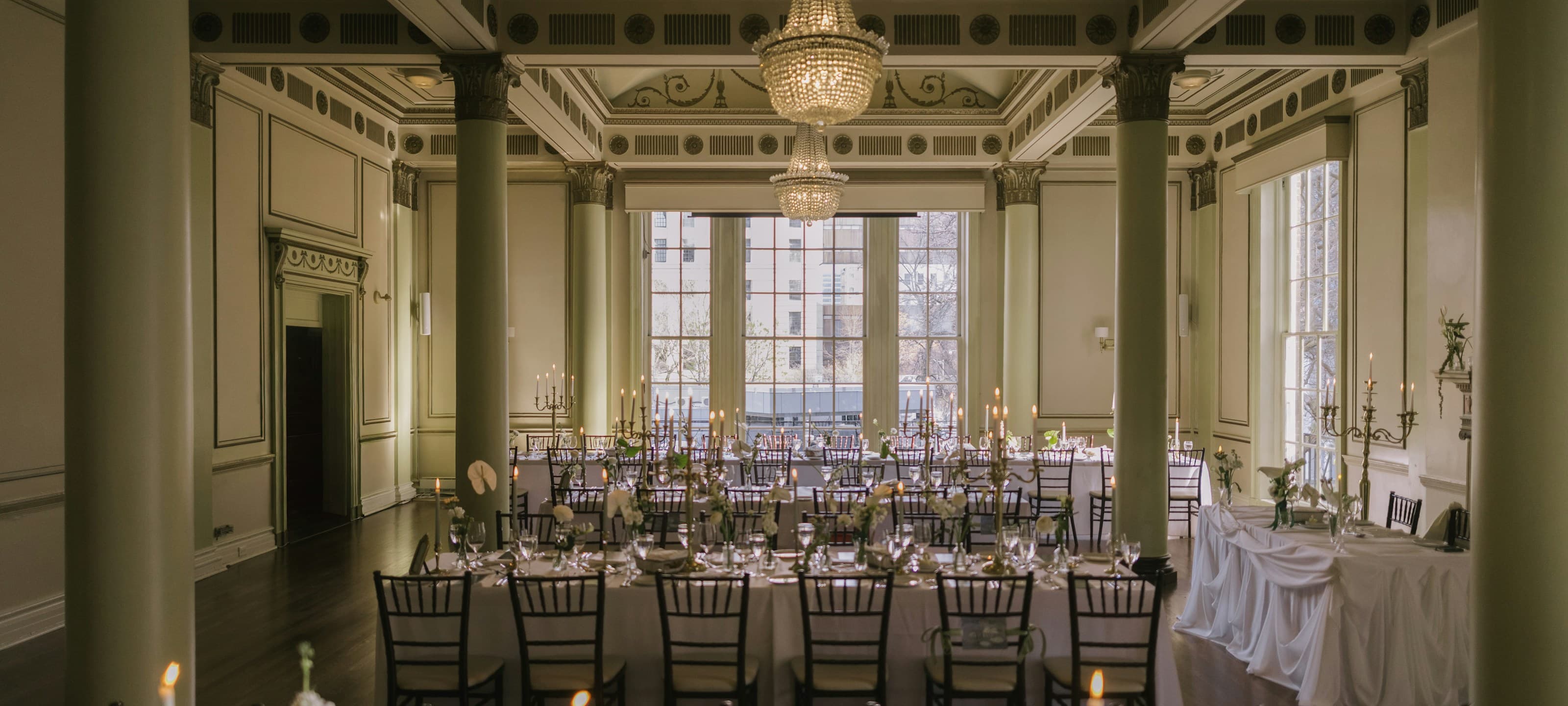 A grand candlelit ballroom with crystal chandeliers, set for a formal dinner